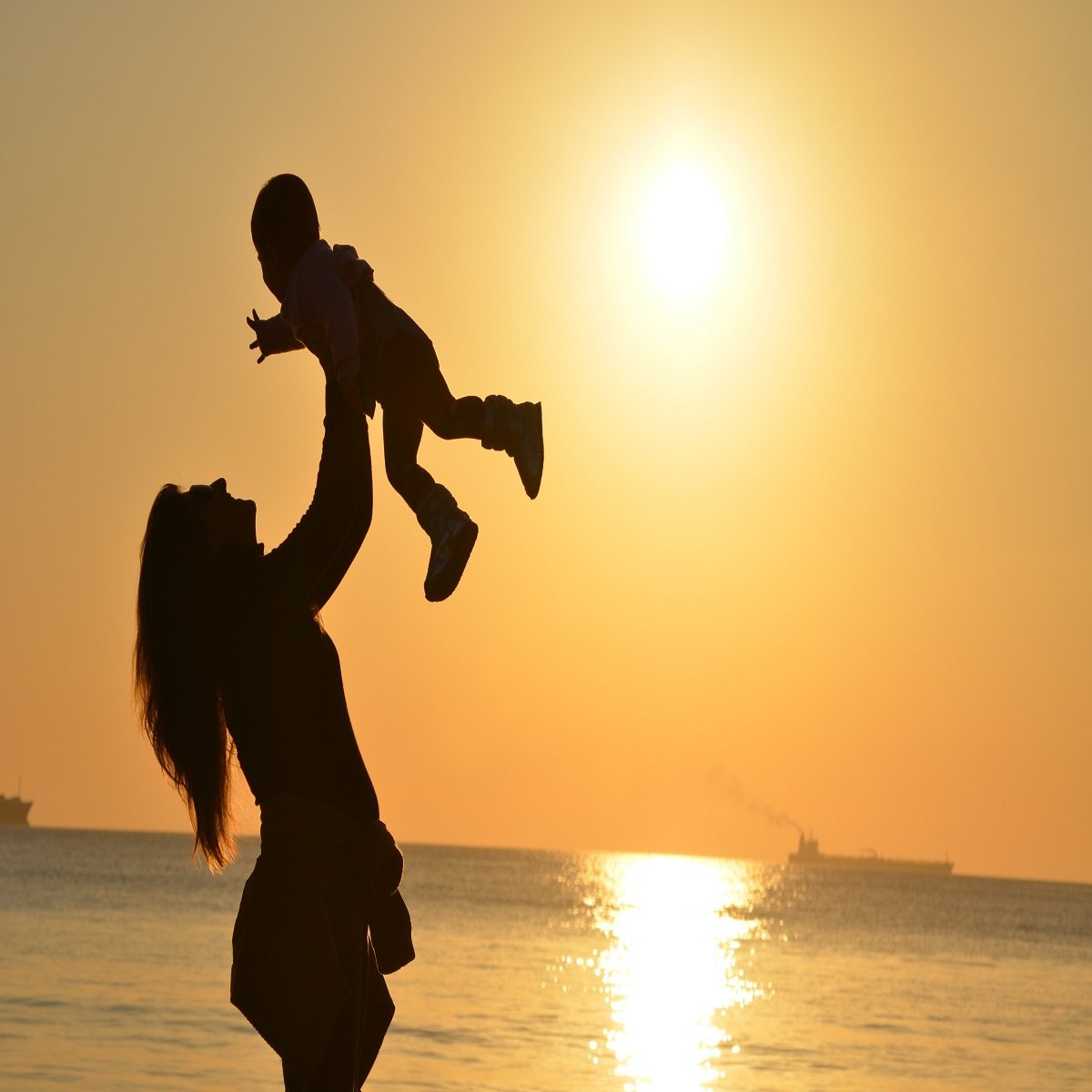woman holding a baby on the beach at the dusk
